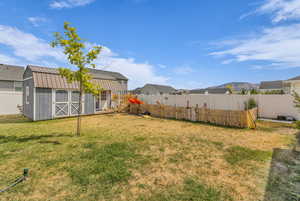 Fenced backyard featuring a storage unit and a residential view