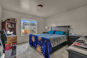 Carpeted bedroom featuring a textured ceiling and baseboards