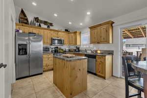 Kitchen featuring stainless steel appliances, dark countertops, vaulted ceiling, recessed lighting, and a kitchen island