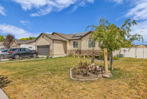 Ranch-style home with stone siding, solar panels, a garage, and a gate