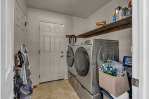 Washroom with washer and clothes dryer and light tile patterned flooring