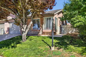Obstructed view of property with a garage, driveway, stucco siding, and stone siding