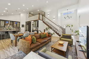 Living area with high vaulted ceiling, stairway, and light wood-style flooring