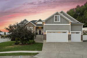 Craftsman house featuring board and batten siding, driveway, brick siding, and an attached garage