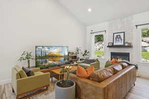 Living area featuring light wood-style flooring, a fireplace, high vaulted ceiling, and recessed lighting