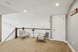 Unfurnished room with recessed lighting, vaulted ceiling, an upstairs landing, carpet flooring, and a textured ceiling