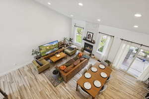 Living room featuring recessed lighting, a large fireplace, wood finished floors, a textured ceiling, and a high ceiling