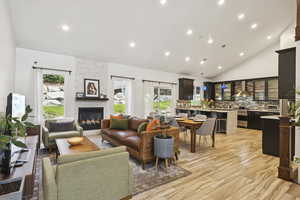 Living area featuring recessed lighting, a fireplace, high vaulted ceiling, and light wood-type flooring