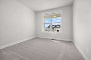 Carpeted spare room featuring baseboards