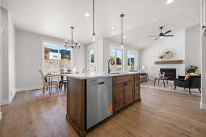 Kitchen with pendant lighting, stainless steel dishwasher, a large fireplace, healthy amount of natural light, and recessed lighting