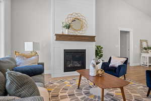 Living room featuring wood finished floors, a fireplace, and high vaulted ceiling