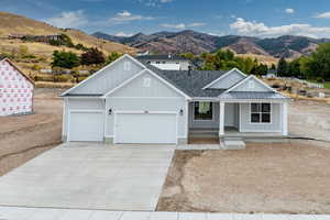 View of front facade with covered porch, a mountain view, driveway, a garage, and board and batten siding