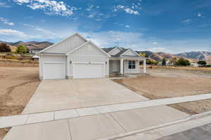 View of front facade featuring board and batten siding, a mountain view, covered porch, concrete driveway, and an attached garage