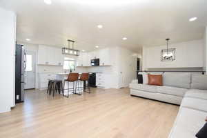 Living area with light wood-style flooring, a chandelier, and recessed lighting