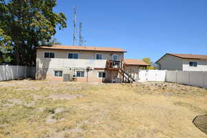 Rear view of house with stairway, a fenced backyard, a deck, and a gate