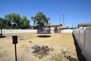 Fenced backyard with a trampoline and stairs