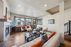 Living area with wood-type flooring, a glass covered fireplace, and recessed lighting