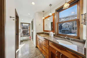 Bathroom with double vanity, stone finish flooring, and recessed lighting
