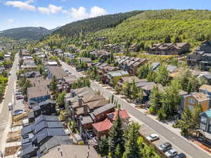 Aerial view of residential area featuring a mountainous background and a heavily wooded area