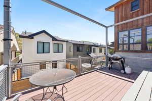 Wooden terrace featuring grilling area, outdoor dining space, and a residential view