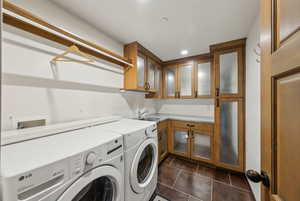 Laundry room featuring independent washer and dryer, cabinet space, dark tile patterned floors, and recessed lighting
