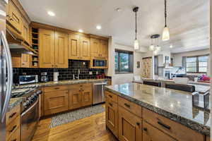 Kitchen featuring light wood finished floors, decorative backsplash, open shelves, stainless steel appliances, and recessed lighting