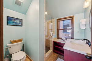 Full bathroom with tiled shower, vanity, and lofted ceiling