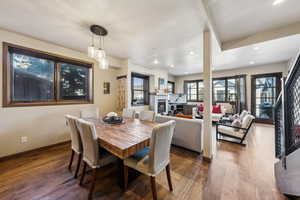 Dining room featuring dark wood-type flooring, a lit fireplace, and recessed lighting