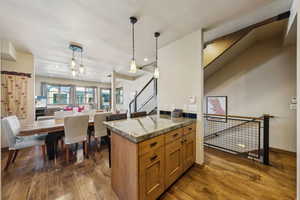 Kitchen featuring dark wood-type flooring, decorative light fixtures, brown cabinets, recessed lighting, and open floor plan