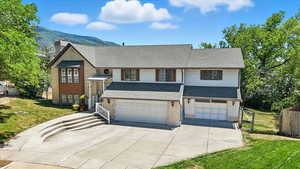 View of front of house featuring a shingled roof, driveway, a garage, and a mountain view