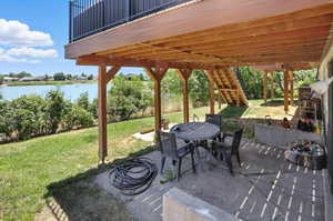 View of patio with outdoor dining space, a water view, and stairs