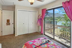 Bedroom featuring access to exterior, carpet flooring, a water and mountain view, a closet, and attic access