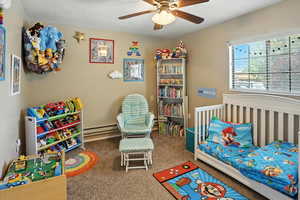 Carpeted bedroom featuring a baseboard heating unit and a ceiling fan