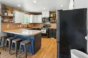 Kitchen with stainless steel appliances, open shelves, a peninsula, white cabinetry, and recessed lighting