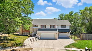 Bi-level home featuring an attached garage, concrete driveway, brick siding, and a shingled roof