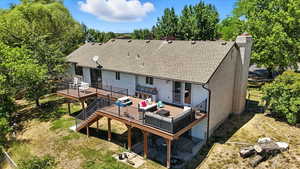 Rear view of house with a deck, a chimney, stairway, and a shingled roof