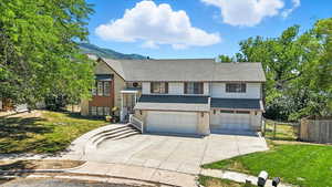 Split foyer home featuring concrete driveway, a garage, a shingled roof, brick siding, and a mountain view