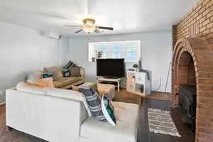 Living area featuring a ceiling fan, a wood stove, and carpet floors