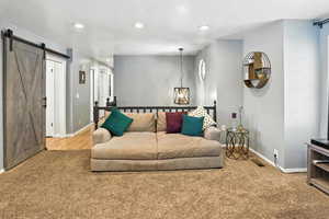Living area featuring a barn door, carpet, and recessed lighting