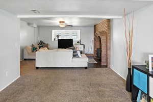 Carpeted living room featuring a ceiling fan and a brick fireplace