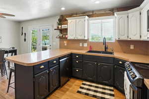 Kitchen featuring dishwasher, range with electric stovetop, white cabinets, a peninsula, and ceiling fan