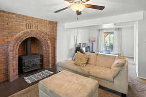 Living area with a wood stove, a ceiling fan, and dark tile patterned flooring