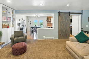 Living room with ceiling fan, a barn door, and recessed lighting