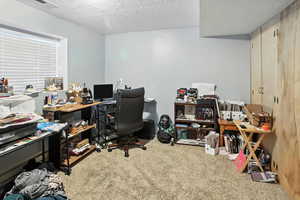 Carpeted office space featuring a textured ceiling
