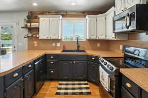 Kitchen featuring electric stove, stainless steel microwave, black dishwasher, white cabinets, and recessed lighting