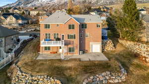 Rear view of property featuring a patio, a residential view, brick siding, a garage, and a deck with mountain view