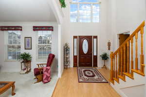 Foyer featuring wood finished floors, stairs, arched walkways, and crown molding