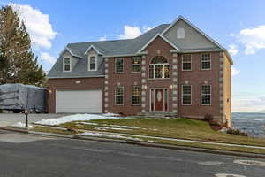 Colonial inspired home with brick siding, a garage, driveway, and a shingled roof