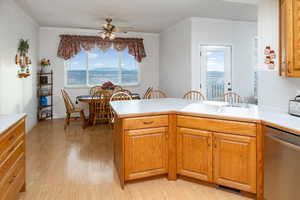 Kitchen featuring stainless steel dishwasher, ornamental molding, light wood-type flooring, light countertops, and ceiling fan