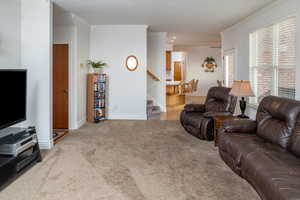 Carpeted living room with crown molding, stairway, and recessed lighting